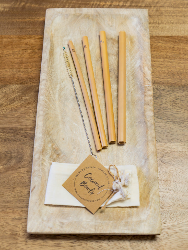Set of bamboo straws on a wooden board with a tag indicating brand.