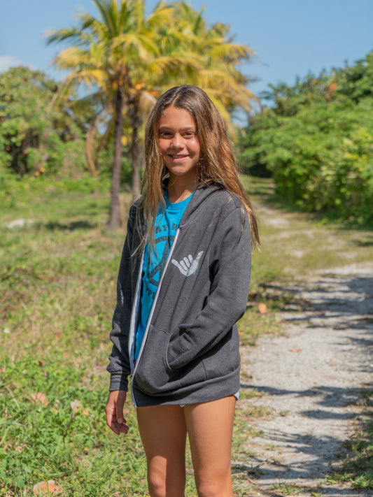 Girl wearing hang loose zip up hoodie on a path with green scenery in the back