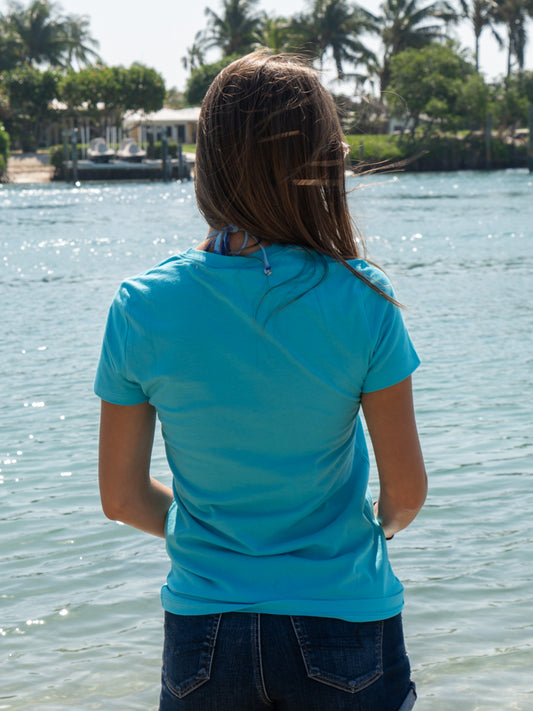 Woman wearing a turquoise t-shirt with water in the background
