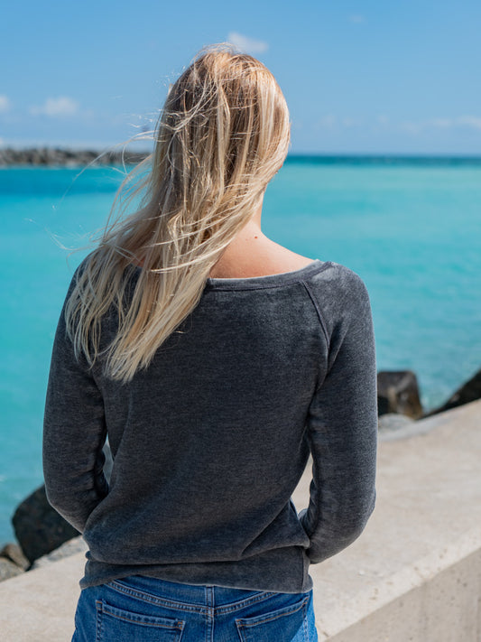 Woman wearing a gray sweatshirt, standing on a beach