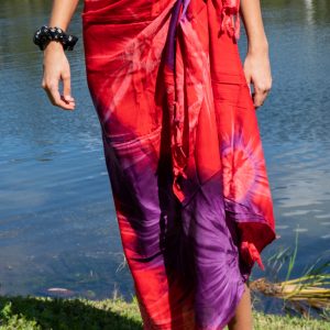 A person standing by water wearing a blue sarong styled as a skirt.