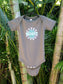 Asphalt colored baby onesie with 'Stay Groovy Baby' text on a hook hanging on a tree