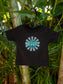 Black t-shirt with 'Stay Groovy Baby' design on a hanger against a green leafy background