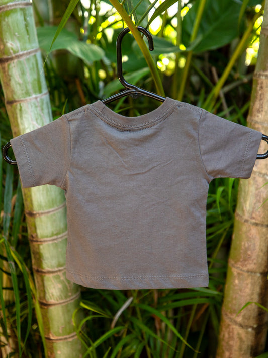 Asphalt t-shirt with design on a hanger against a green leafy background
