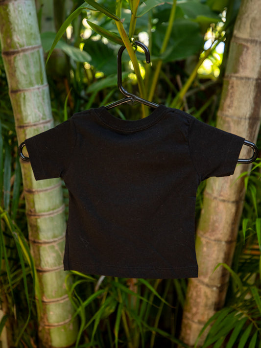 Black t-shirt with design on a hanger against a green leafy background