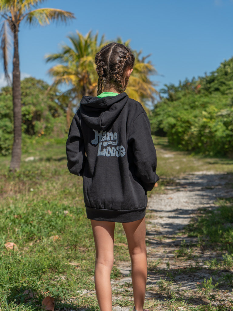 Young girl wearing a black hoodie with the words 'Hang Loose' on the back