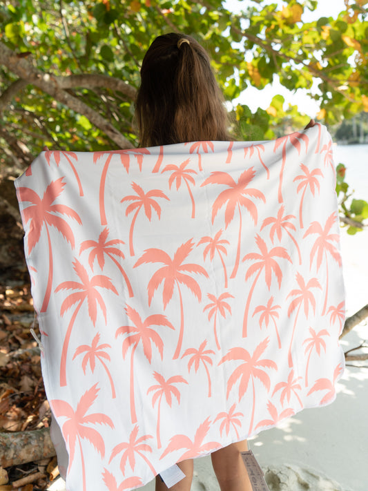 Person holding a pink palm tree patterned towel outdoors