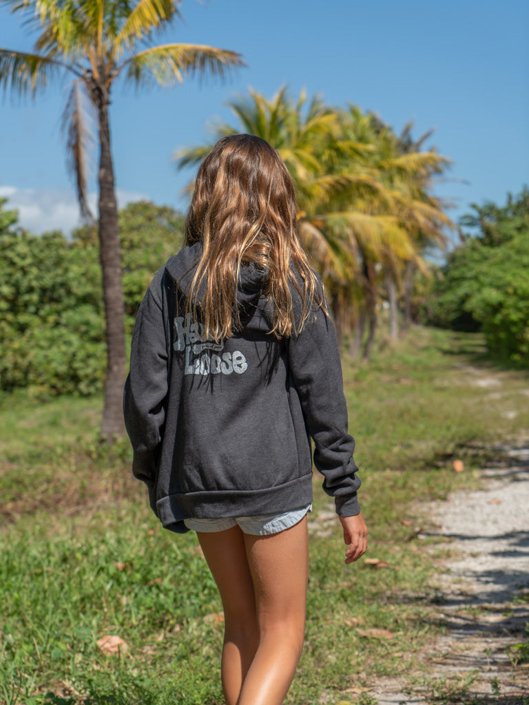 Girl walking wearing a dark gray hoodie with the words 'Hang Loose' on the back