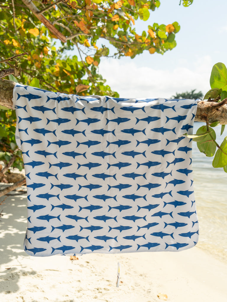 Towel hanging on tree branch with shark pattern on the beach.