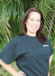 Woman wearing black Jay Robb Emoji Tee, standing with a leafy background