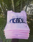 Pink 'Guru of Peace' shirts stacked with palm tree leaves in the background.