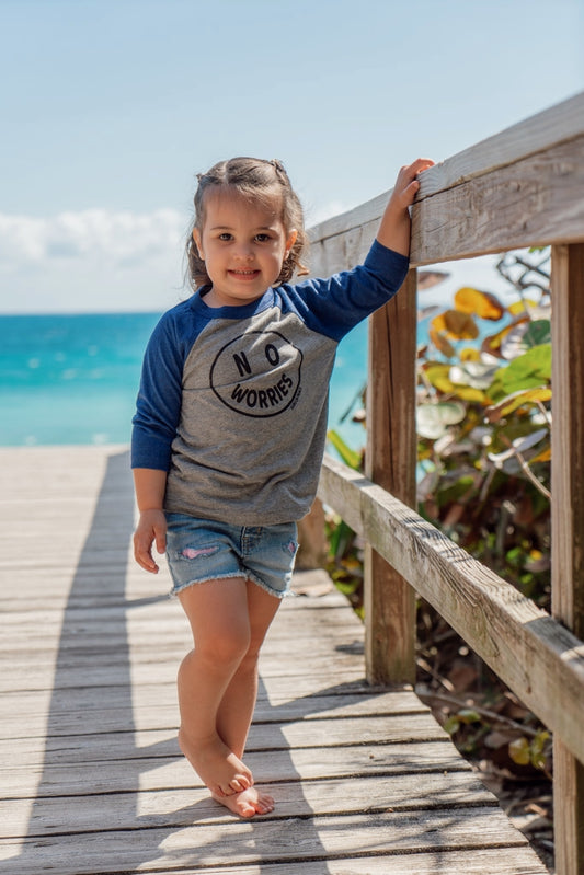 Child standing on a wooden boardwalk by the ocean