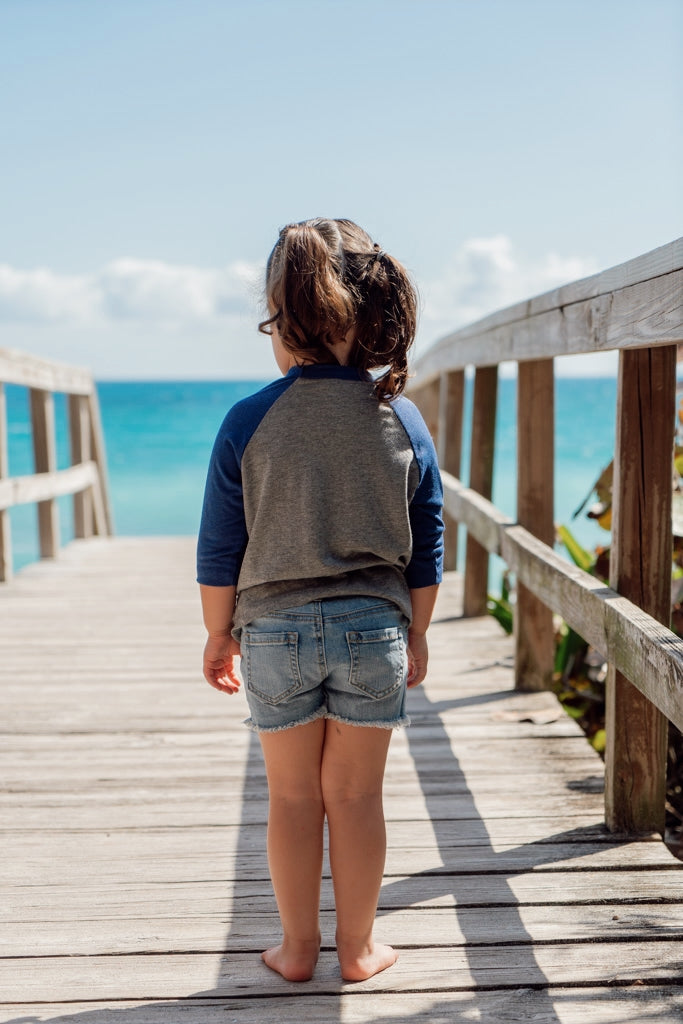 Child standing on a wooden boardwalk by the ocean