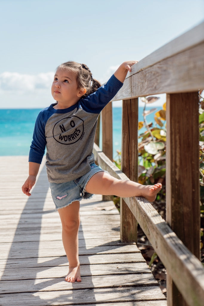 Child standing on a wooden boardwalk by the ocean