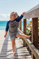 Child standing on a wooden boardwalk by the ocean