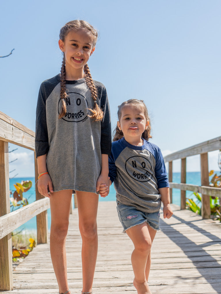 Children standing on a wooden boardwalk by the ocean