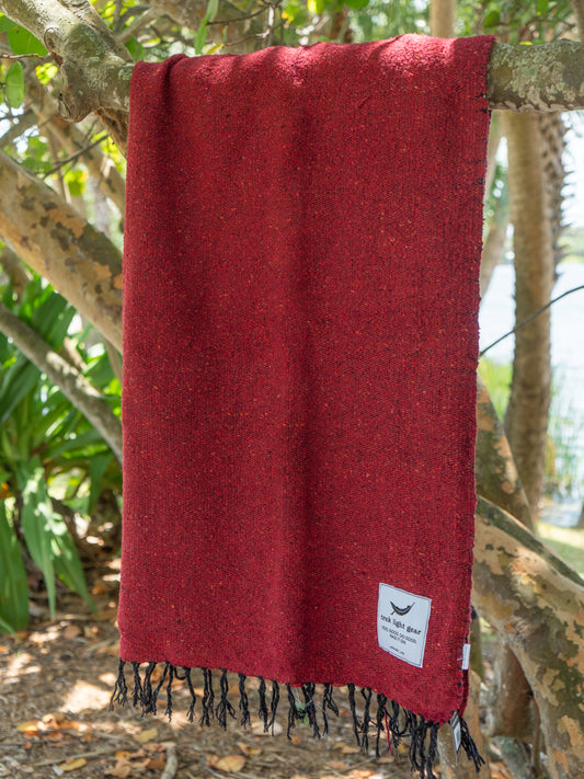 Red blanket hanging on a tree branch in a beach setting