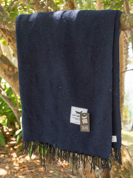 Navy blanket hanging on a tree branch in a beach setting