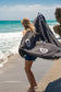 Person holding a charcoal poncho behind their back with white peace signs by a body of water.