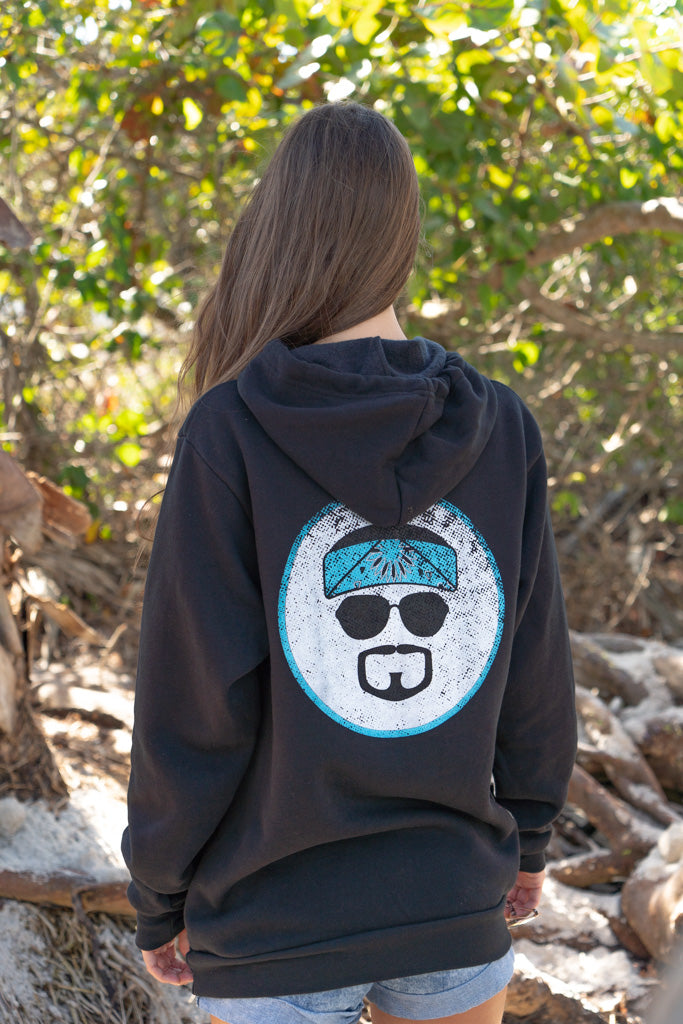 Woman wearing a black hoodie with a logo, standing outdoors.