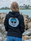 Woman wearing a black hoodie with a logo, standing outdoors.