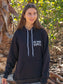 Woman wearing a black hoodie with 'Die Hard Hippie' text, standing outdoors.