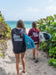 Two people walking on a beach with surfboards, wearing 'Hang Loose' hoodies.