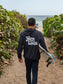 Man walking on beach wearing dark grey hoodie with the words 'Hang Loose' on the back