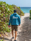 Man wearing blue hoodie with a the word 'Peace', walking on a beach