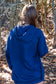 Woman wearing blue hoodie with trees in the background