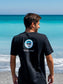 Man wearing a black t-shirt with 'Hang Loose' logo on the beach
