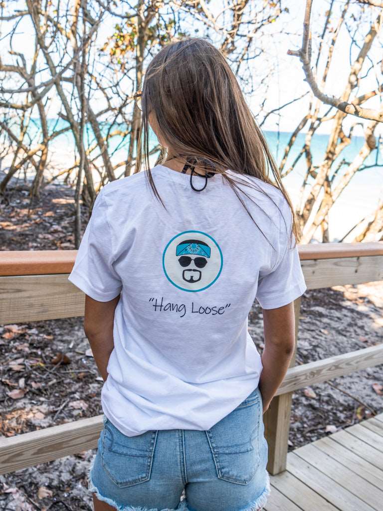 Man wearing a white t-shirt with 'Hang Loose' logo on the beach
