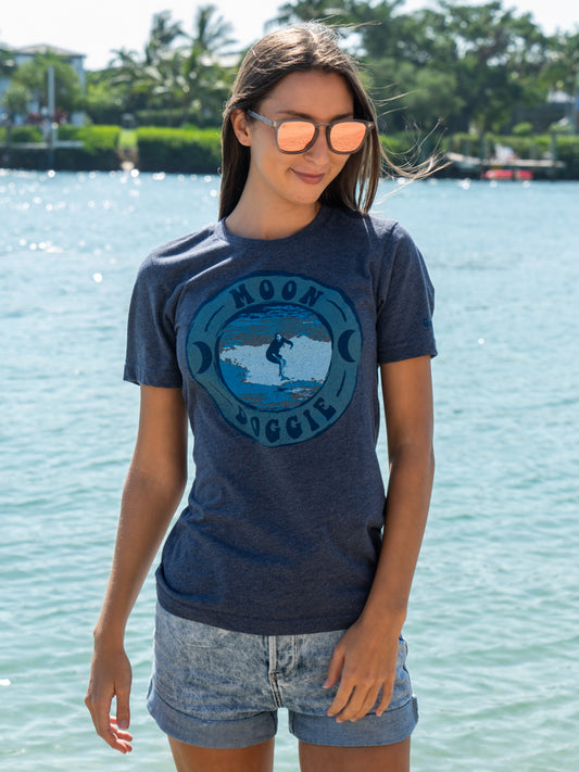Woman wearing a blue t-shirt with a graphic design by a body of water