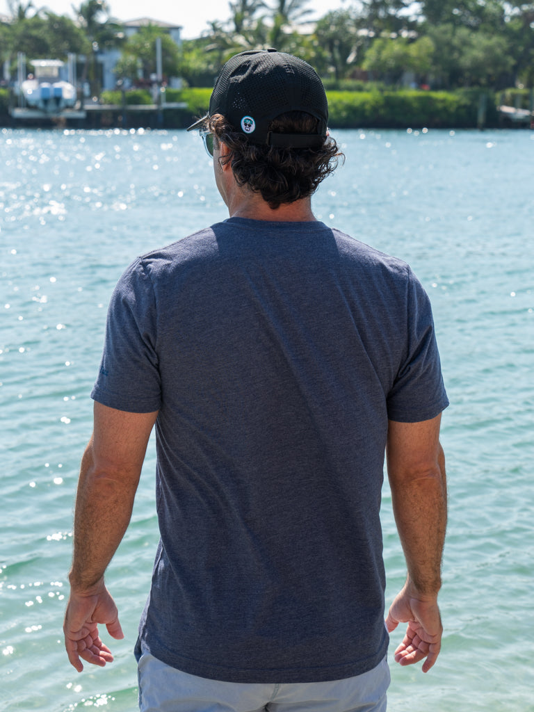 Man wearing a blue t-shirt by a body of water