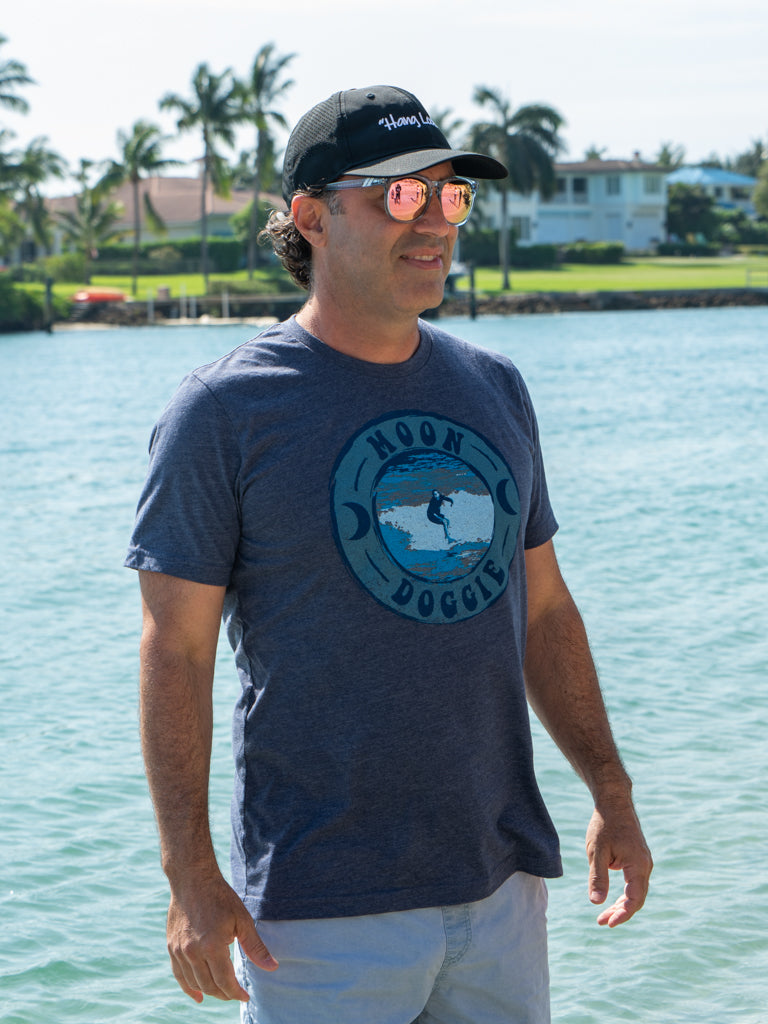 Man wearing a blue t-shirt with a graphic design by a body of water