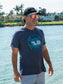 Man wearing a blue t-shirt with a graphic design by a body of water