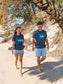 Man and woman walking wearing matching blue t-shirts with a design