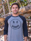 Man wearing a 'No Worries' shirt standing in front of wooden logs.