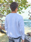 Man wearing a white sweatshirt by a body of water with trees in the background