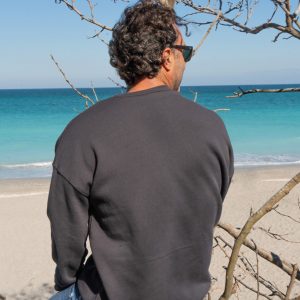 Man sitting on a wooden railing with sunglasses and a black sweatshirt