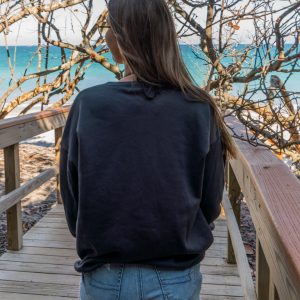 Woman standing on a wooden boardwalk with sunglasses and a black sweatshirt