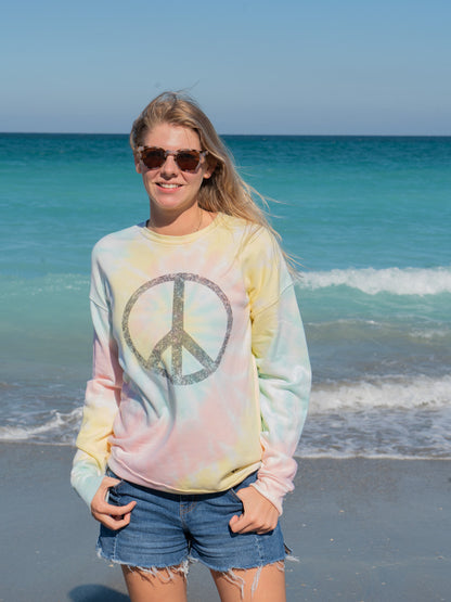 Woman wearing a tie-dye sweatshirt with a peace symbol on a beach