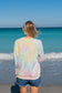 Woman wearing a tie-dye sweatshirt with a peace symbol on a beach