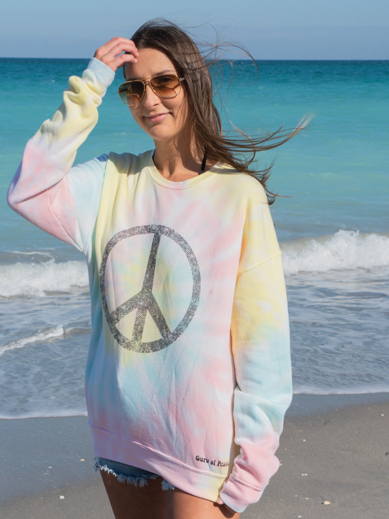 Woman wearing a tie-dye sweatshirt with a peace symbol on a beach