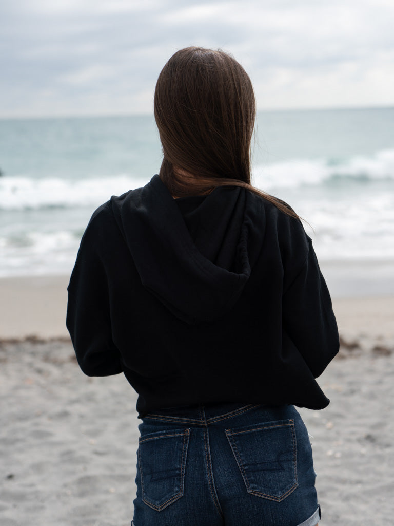 Woman wearing a black hoodie on a beach