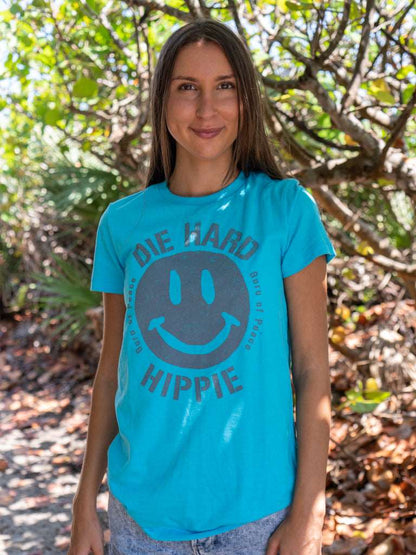 Woman wearing a turquoise t-shirt with a smiley face design with trees in the background