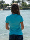 Woman wearing a turquoise t-shirt with water in the background
