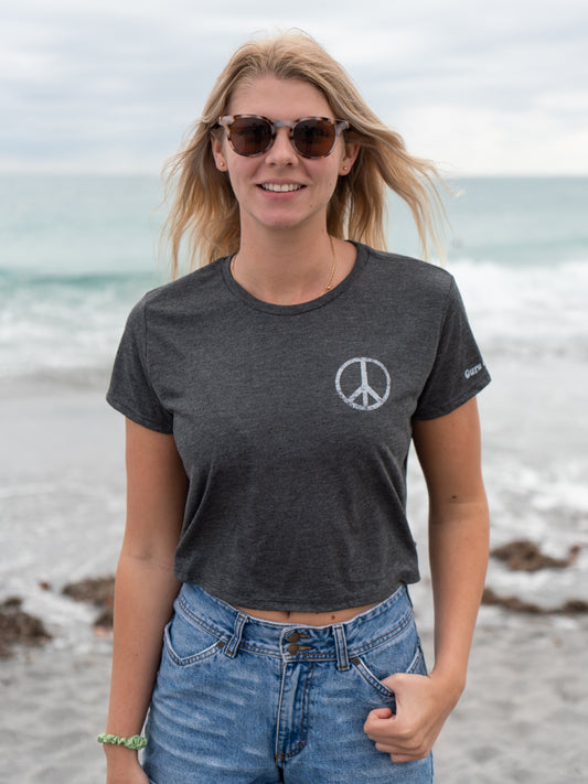 Woman wearing a dark gray t-shirt with a peace symbol on a beach