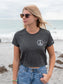 Woman wearing a dark gray t-shirt with a peace symbol on a beach