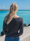 Woman wearing a gray sweatshirt, standing on a beach